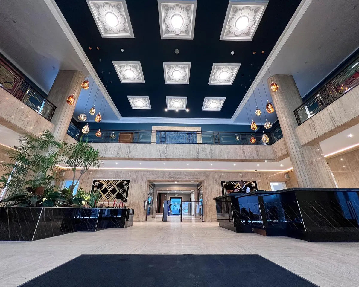 A double-volume office lobby with a lit coffered ceiling, planters and a reception desk