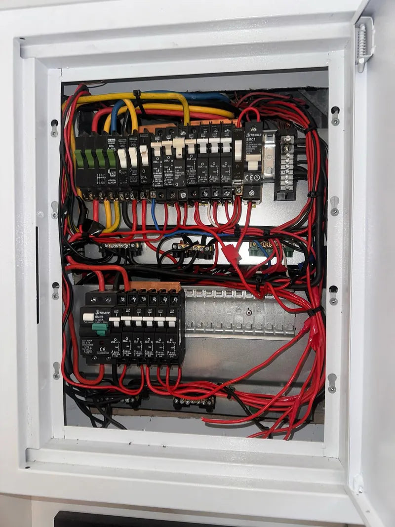 An open distribution board with neatly routed red and black wiring and rows of breakers