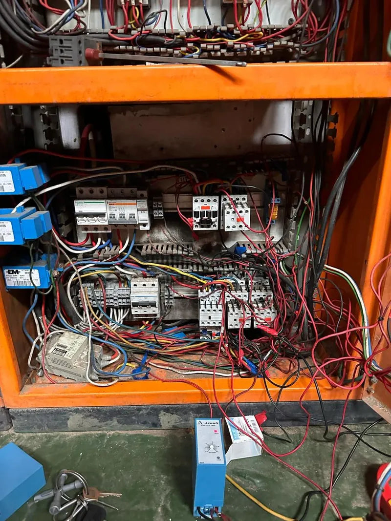 An open control panel with contactors, breakers and loose wiring