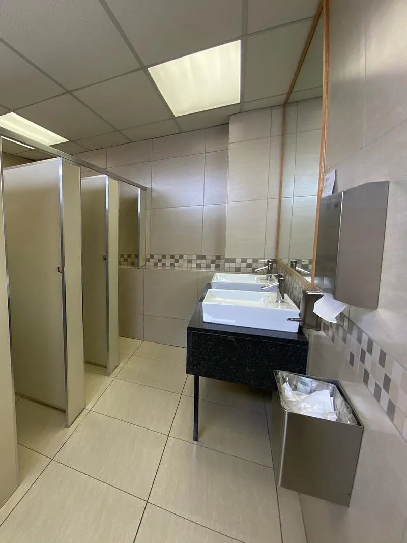 A commercial washroom with toilet cubicles and a counter with basins