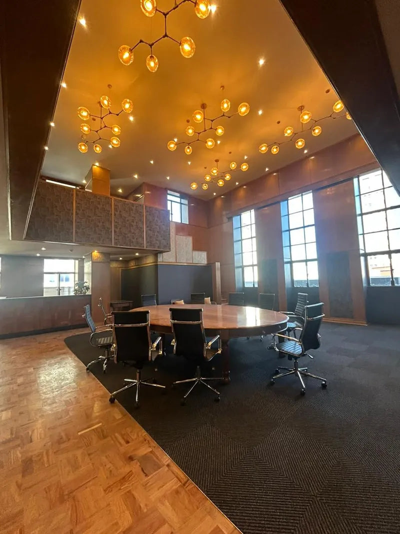 A boardroom with clusters of pendant lights and downlights above a round table