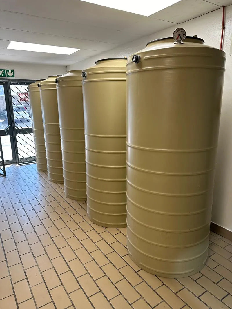 A row of beige water tanks installed inside a commercial building