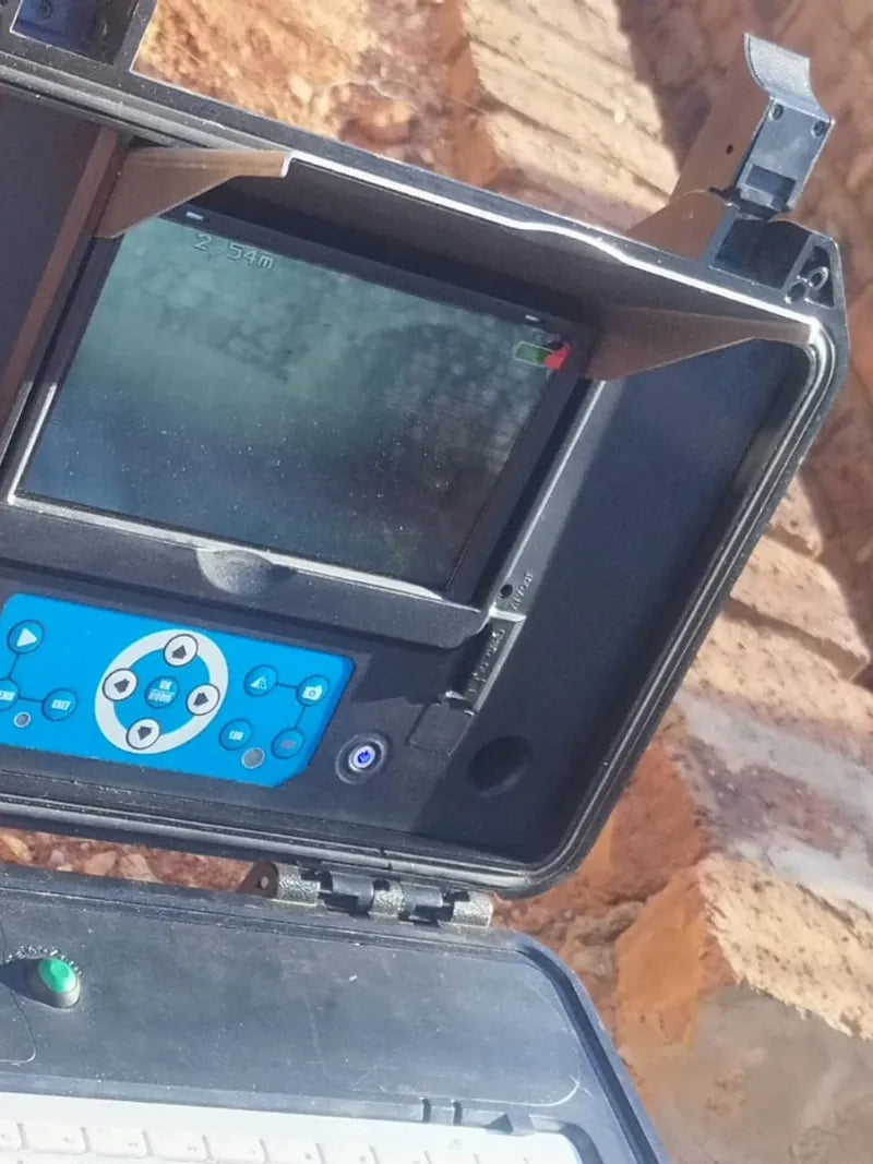 A hand opening the monitor case of a drain inspection camera