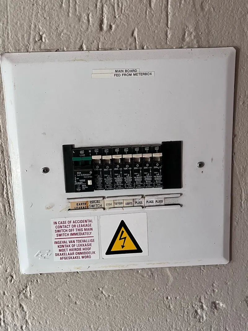 A household main distribution board with labelled breakers and a safety notice
