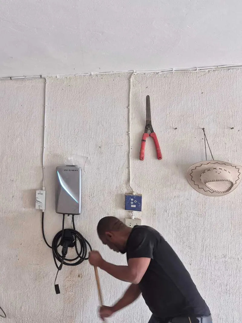 A technician working below a newly mounted EV charger in a home garage