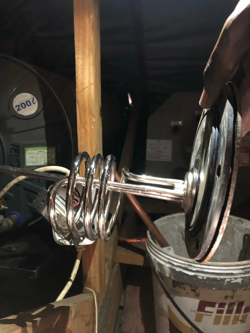 A geyser heating element being drawn out of a geyser in a roof space