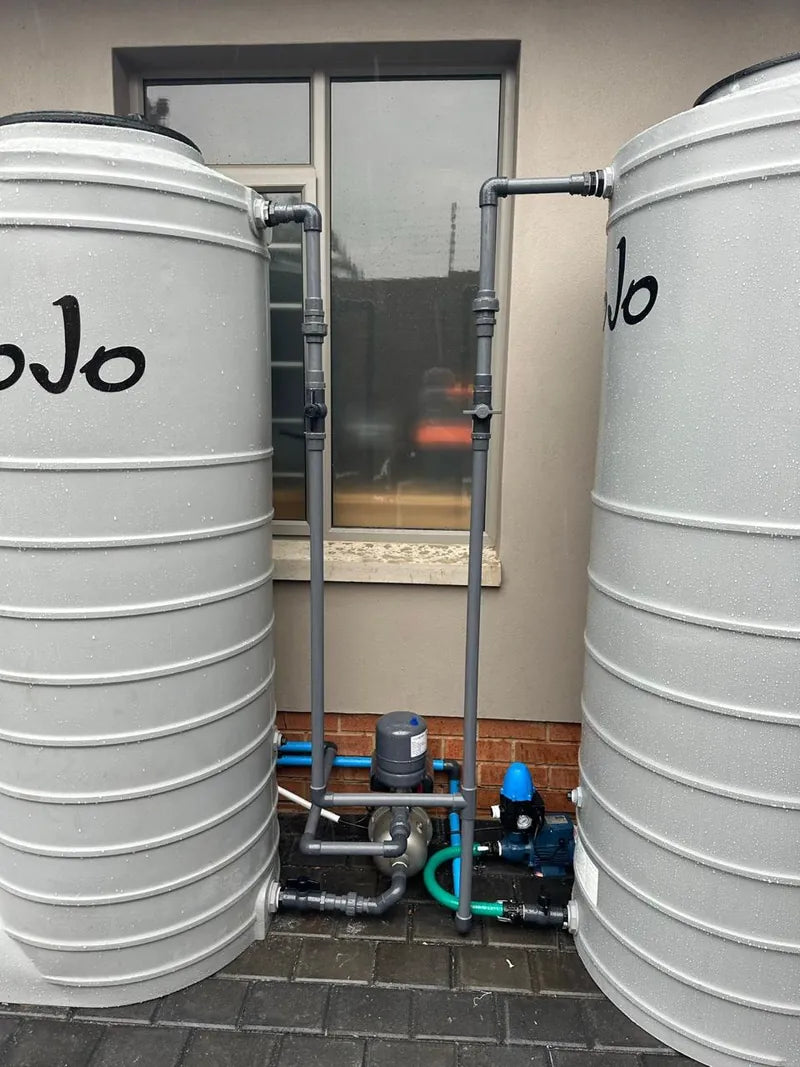 Two white JoJo water tanks with a pump and filter installed between them