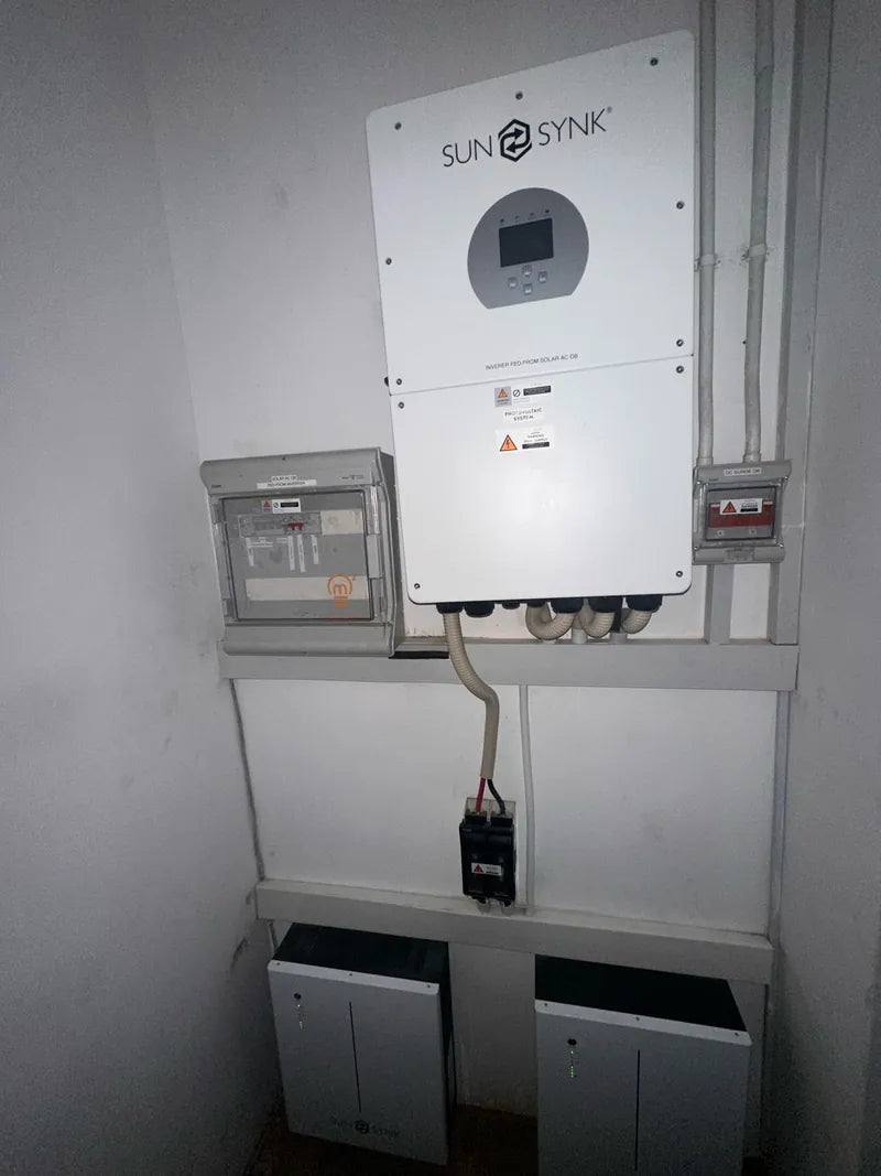 A hybrid inverter with isolator boxes and two batteries mounted on a wall