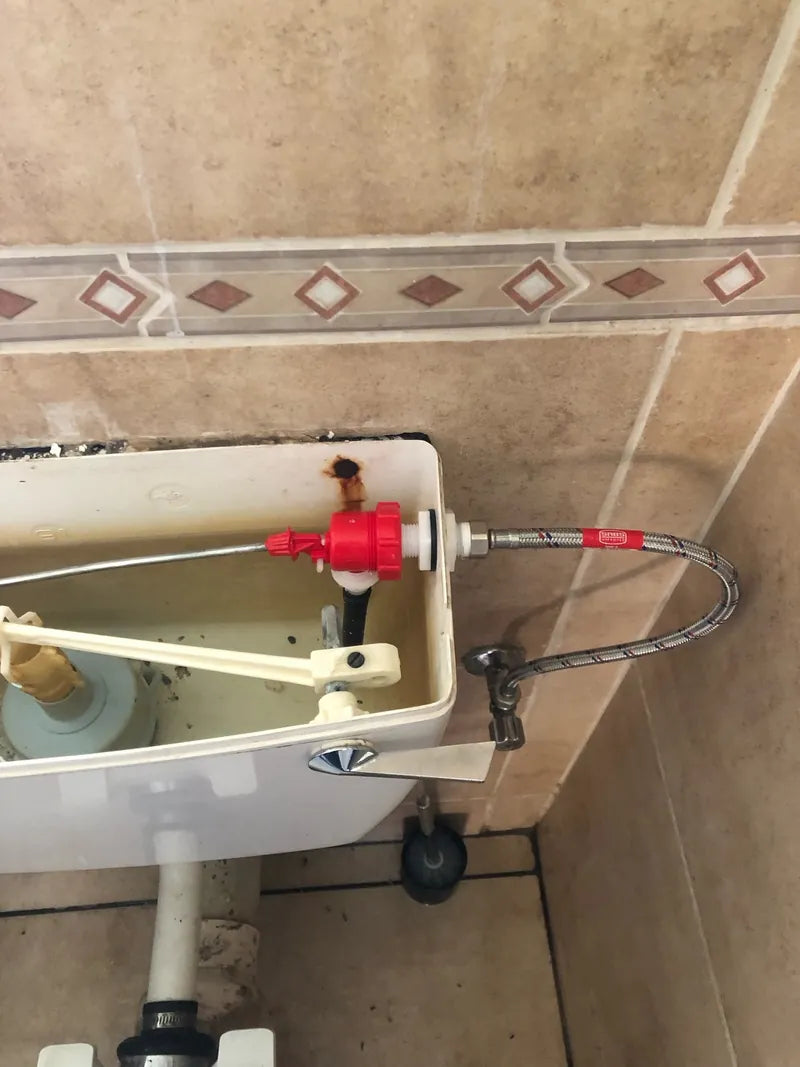 An open toilet cistern with a new fill valve and braided supply hose