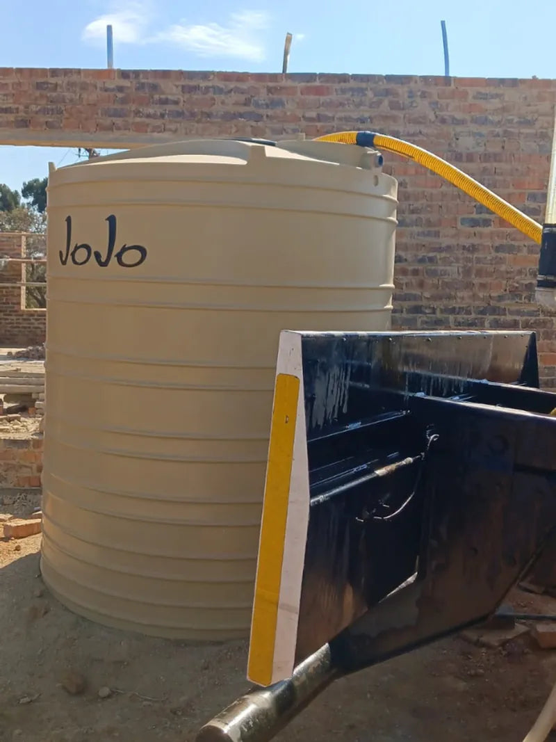A JoJo water tank being filled through a yellow hose from a water trailer
